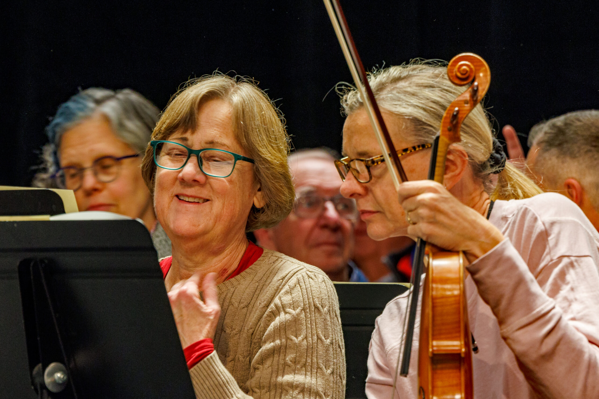 Orchestra musicians smiling during a rehearsal